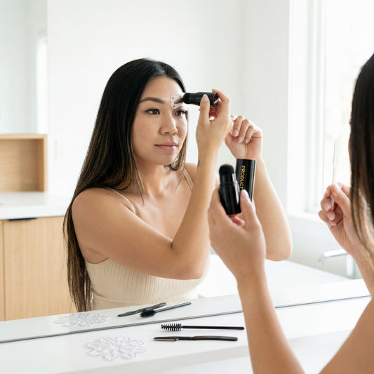 Vrouw brengt een wenkbrauwstempel aan tijdens een rustige ochtendroutine met natuurlijk licht.