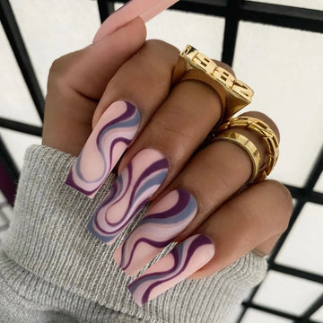 Een close-up van een nagel bedekt met een swirl nail art design in pastelkleuren.